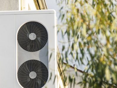 Eine Wärmepumpe steht vor einer Hauswand