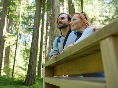 Paar im Wald blickt nachdenklich umher. Verdeutlicht die Verbindung zur Natur beim Wechsel zu Ökogas-Tarifen.