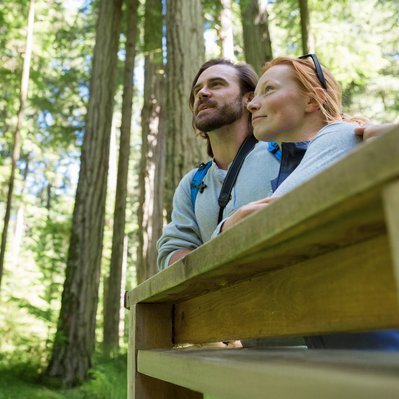 Paar im Wald blickt nachdenklich umher. Verdeutlicht die Verbindung zur Natur beim Wechsel zu Ökogas-Tarifen.