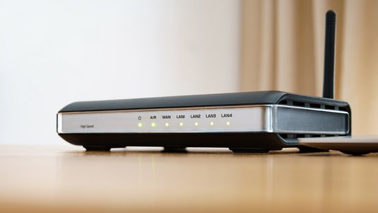 Videoanleitung zur Einrichtung: DSL-Router mit leuchtenden LEDs auf Holztisch, Symbol für funktionierenden Internetanschluss.