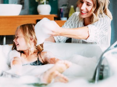 Bild zeigt eine Frau, die ihre Tochter badet, als Symbolbild für Warmwasser-Kosten