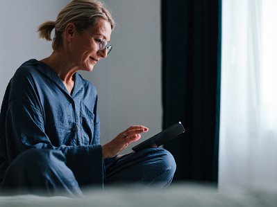 Frau im Wohnzimmer recherchiert am Tablet über Wärmepumpe Nachteile.