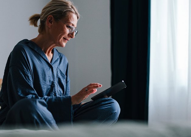 Frau im Wohnzimmer recherchiert am Tablet über Wärmepumpe Nachteile.