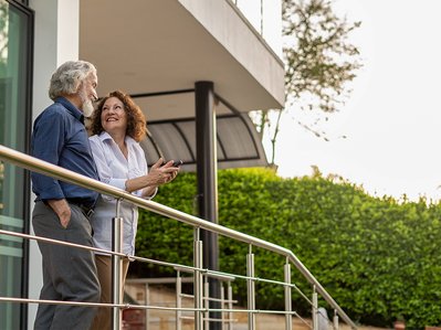 Paar auf moderner Terrasse, zeigt Zufriedenheit und informiert über ENTEGA Fragen zu Vertragslaufzeit und Konditionen.