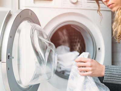 Bild zeigt Frau beim Beladen der Waschmaschine – effizientes Waschen hilft, Strom und Kosten zu sparen.