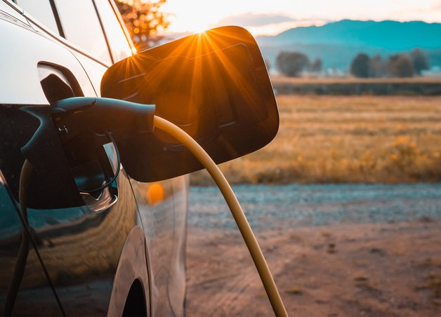 Ladekabel verbindet Elektroauto mit Wallbox Photovoltaik, Sonnenlicht im Hintergrund, Symbol für umweltfreundliche Energieversorgung.