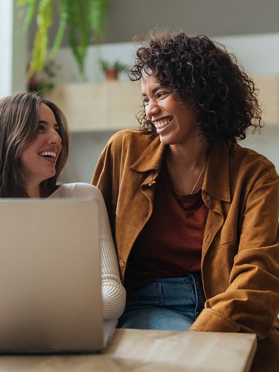 Zwei Frauen im Gespräch, gemütliche Atmosphäre mit Pflanzen und Laptop. Symbolisiert Informationen zu Formularen und Services für ENTEGA Kunden.