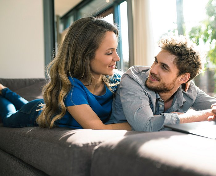 Paar entspannt auf Sofa, nutzt Laptop, symbolisiert Vorteile von Highspeed-Internet im Odenwaldkreis durch Glasfaseranschluss.
