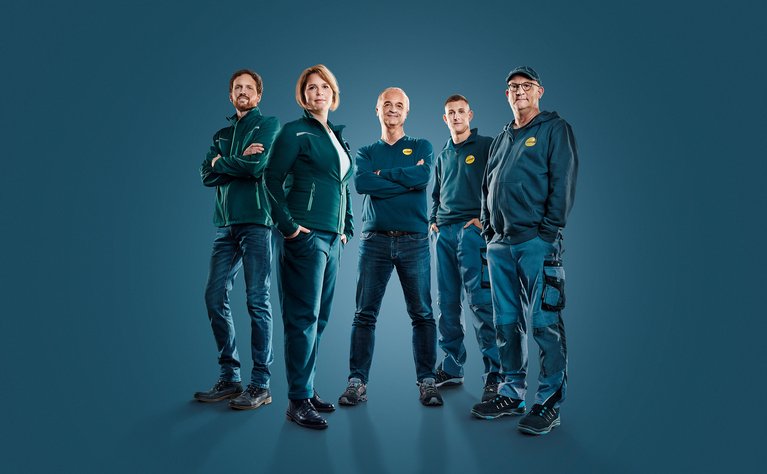 Fünfköpfiges Team in Arbeitskleidung, lächelnd und selbstbewusst. Symbolisiert Kompetenz in energetischer Sanierung mit individuellem Plan.