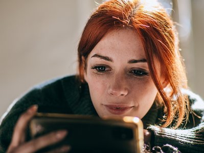 Bild zeigt Frau, die auf ihr Handy schaut – Thema: Stromverbrauch mit einer App messen und verfolgen.