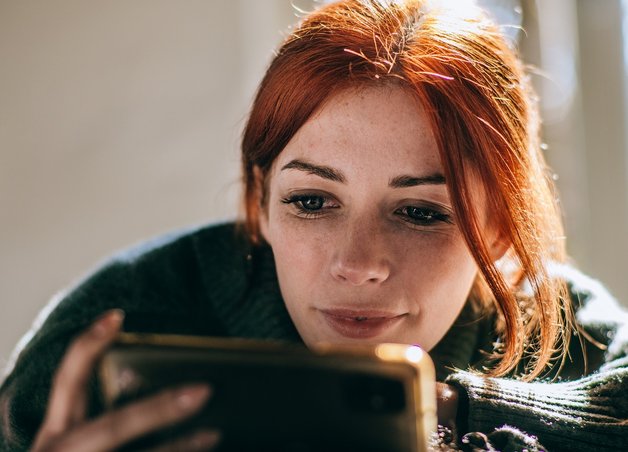 Bild zeigt Frau, die auf ihr Handy schaut – Thema: Stromverbrauch mit einer App messen und verfolgen.