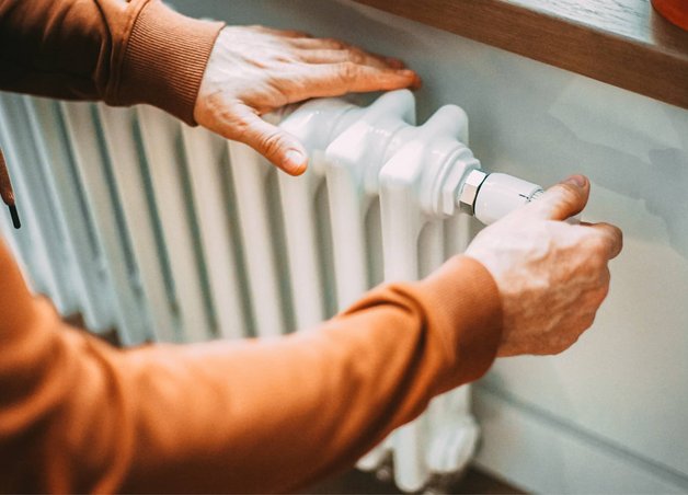 Bild zeigt eine Hand, die an einem Heizkörper-Thermostat dreht, als Symbolbild für das Thema „Brennwert von Gas“