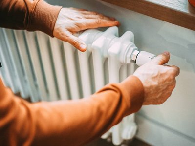 Bild zeigt eine Hand, die an einem Heizkörper-Thermostat dreht, als Symbolbild für das Thema „Brennwert von Gas“