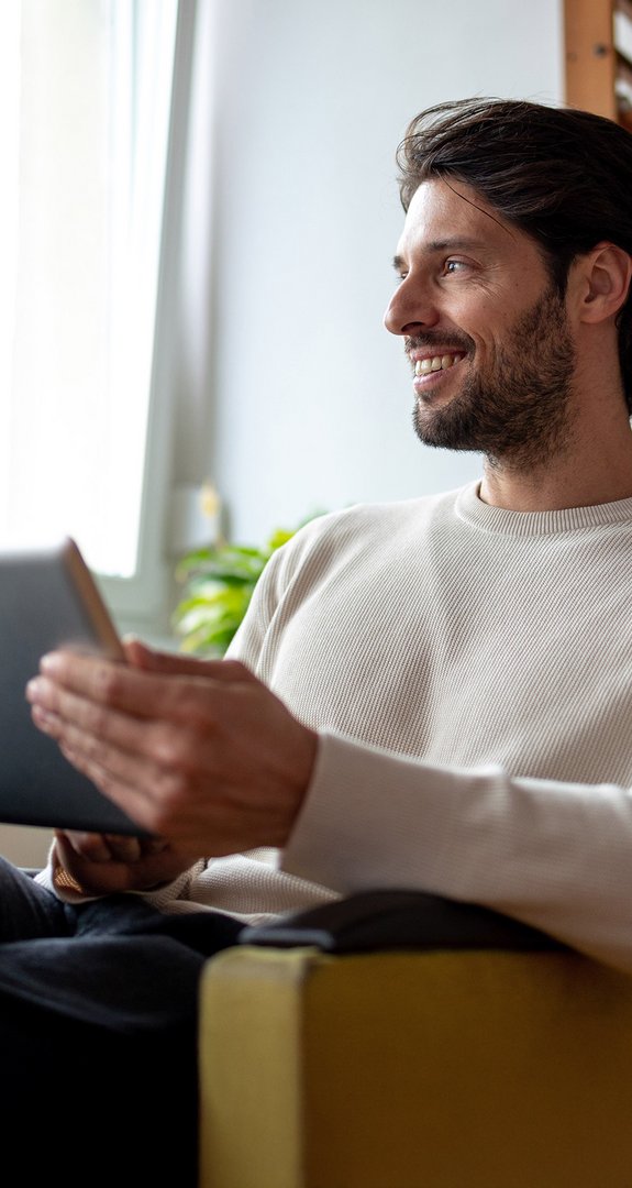 Person mit Tablet in gemütlicher Umgebung, erkundet Informationen zu ENTEGA Kündigung und Umzug.