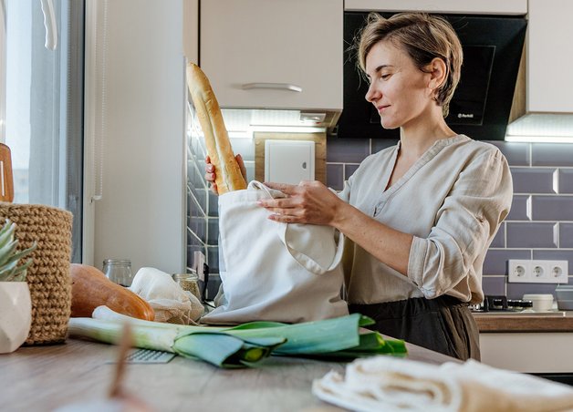 Müllvermeidung Tipps: Eine Frau nutzt wiederverwendbare Beutel für Lebensmittel, um Plastikmüll beim Einkaufen in der Küche zu reduzieren.