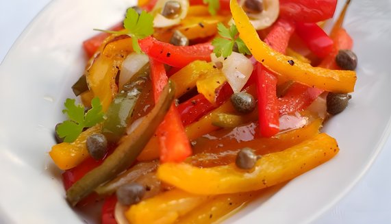 Geschmorte Paprika in Rot, Gelb und Grün mit Kapern und frischer Petersilie auf einem Teller, mediterranes Sommergericht.